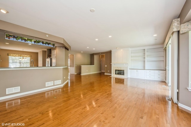 14112 Redmond Dr, Huntley, IL 60142 - unfurnished living room with a notable chandelier, baseboards, light wood-type flooring, and visible vents