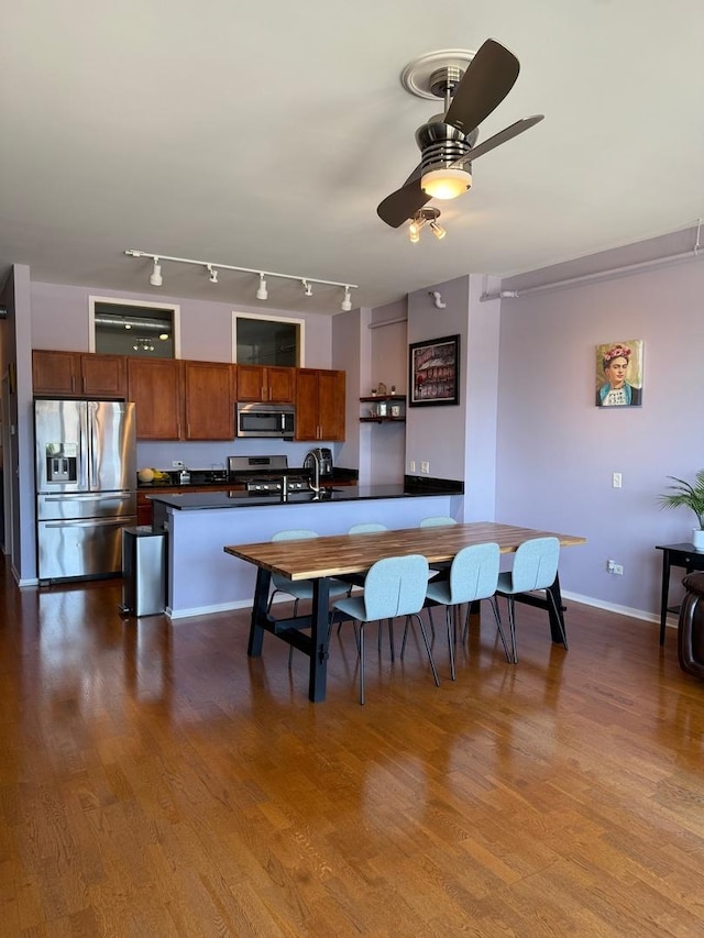 dining room featuring rail lighting, baseboards, ceiling fan, and dark wood-style floors