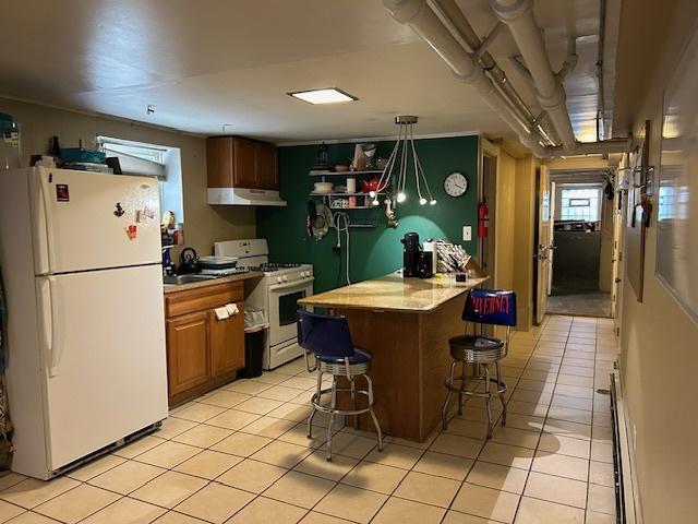 3717 W Addison St, Chicago, IL 60618 - kitchen with under cabinet range hood, a breakfast bar, white appliances, and light tile patterned floors