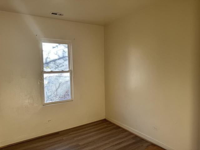 spare room with baseboards, dark wood-style flooring, and visible vents