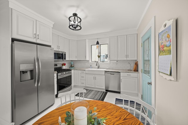 kitchen featuring stainless steel appliances, a sink, backsplash, white cabinetry, and ornamental molding