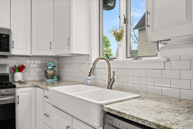 kitchen featuring appliances with stainless steel finishes, a sink, white cabinets, and decorative backsplash