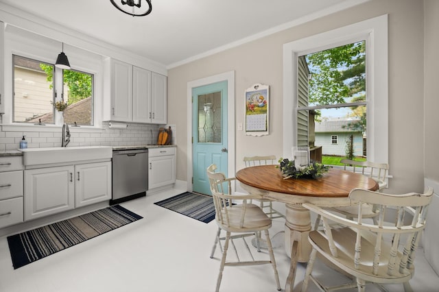 kitchen featuring dishwasher, a sink, decorative backsplash, healthy amount of natural light, and crown molding