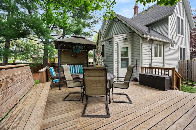wooden terrace featuring a fenced backyard, a gazebo, and outdoor dining space
