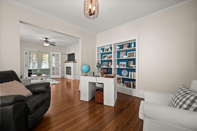 living room with dark wood-style floors, crown molding, a fireplace, ceiling fan, and baseboards