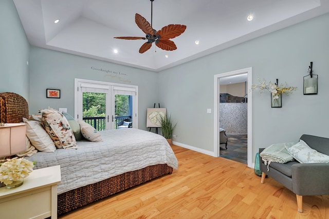 bedroom featuring access to outside, wood finished floors, a raised ceiling, french doors, and baseboards