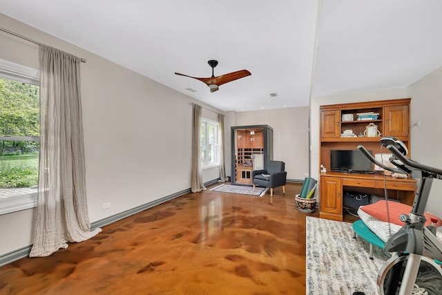 sitting room with baseboards, ceiling fan, and concrete flooring