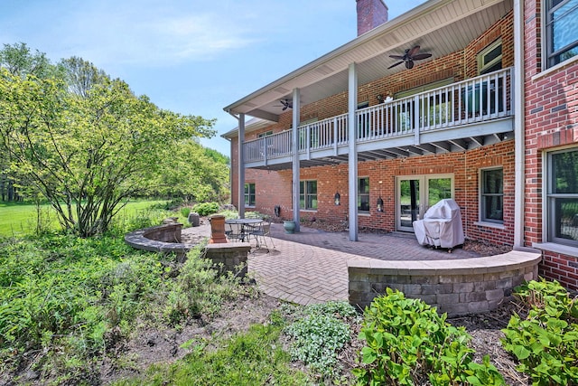rear view of property featuring ceiling fan, brick siding, a balcony, a patio, and a chimney