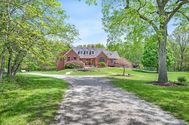 view of front of home with a front lawn, a chimney, and brick siding