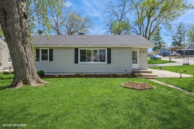 ranch-style house featuring roof with shingles and a front yard