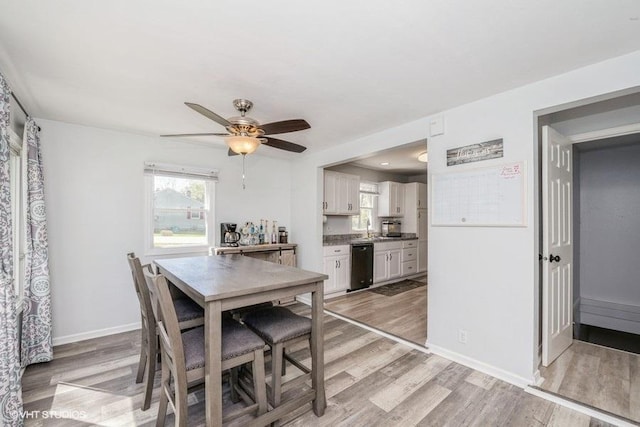 dining area with a ceiling fan, baseboards, and light wood-type flooring