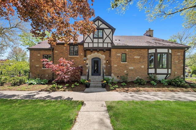 946 N Marion St, Oak Park, IL 60302 - tudor home with a chimney, brick siding, a front yard, and a shingled roof