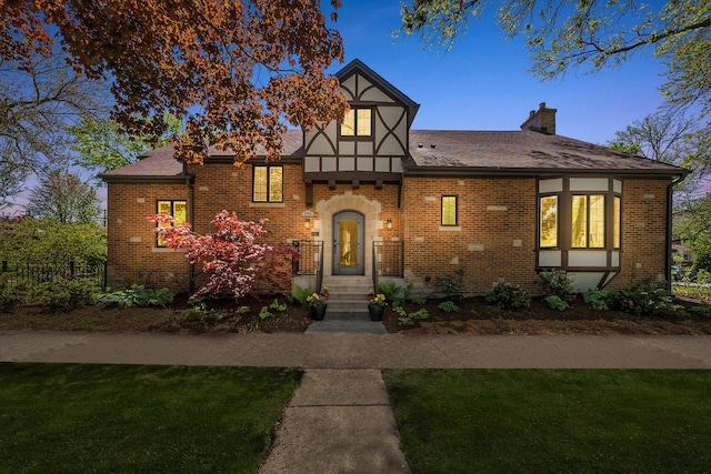 946 N Marion St, Oak Park, IL 60302 - tudor home featuring a chimney, a front lawn, brick siding, and roof with shingles