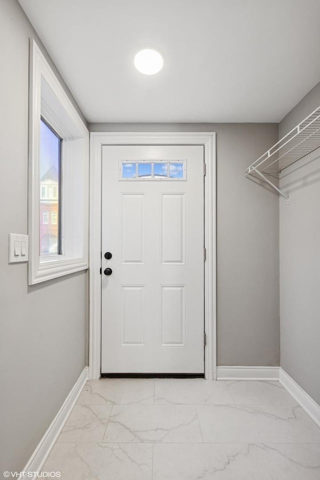 doorway with baseboards and marble finish floor