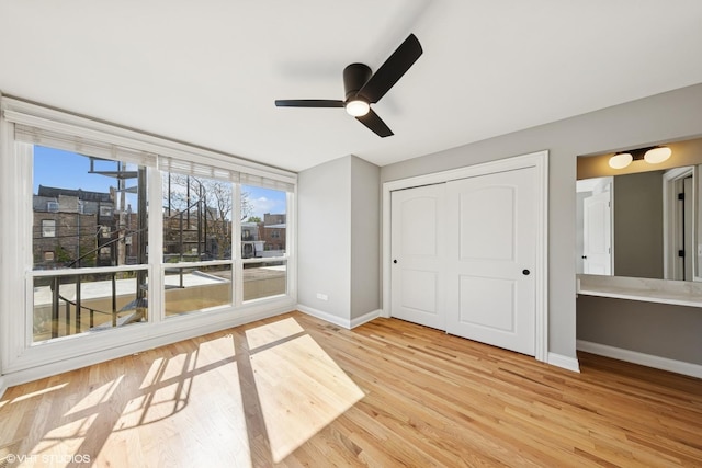 unfurnished bedroom with a closet, wood finished floors, baseboards, and a ceiling fan