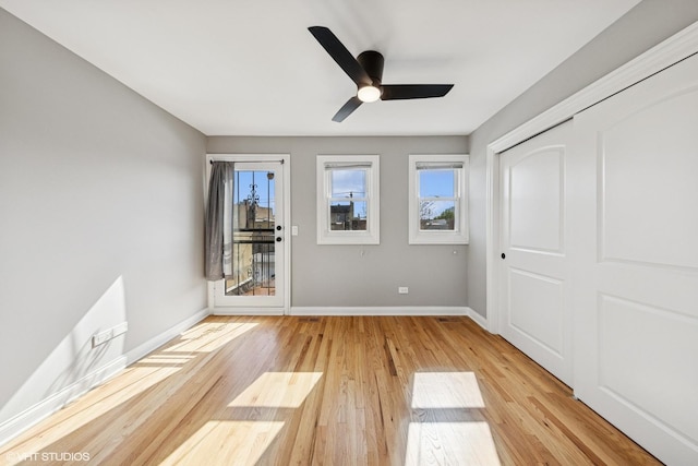 unfurnished bedroom with a closet, light wood-type flooring, baseboards, ceiling fan, and access to outside