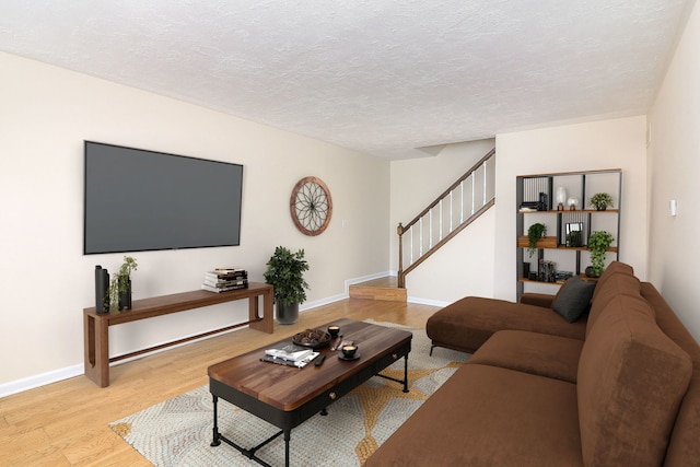 living area with stairway, light wood finished floors, a textured ceiling, and baseboards