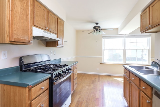 kitchen featuring appliances with stainless steel finishes, under cabinet range hood, a ceiling fan, light wood-type flooring, and a sink