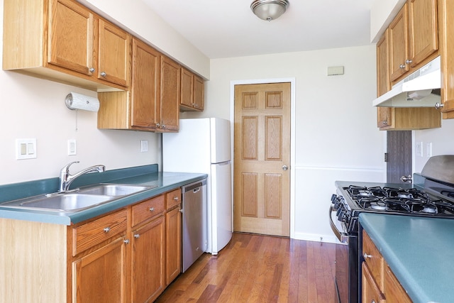 kitchen with gas range oven, under cabinet range hood, a sink, dishwasher, and dark wood-style floors