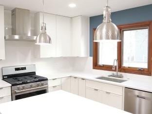 kitchen featuring white cabinetry, light countertops, appliances with stainless steel finishes, and wall chimney exhaust hood