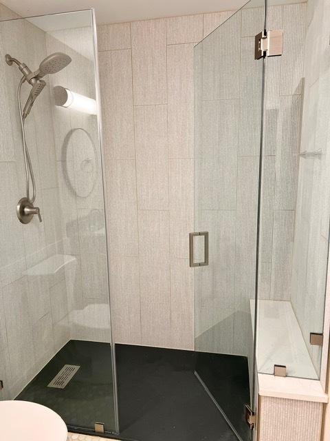 bathroom featuring toilet, a shower stall, and visible vents
