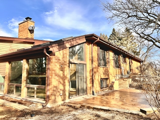 view of side of home with brick siding and a chimney
