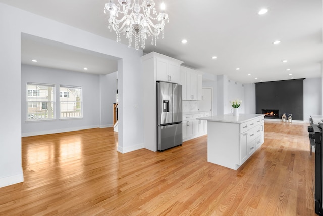 20445 Spirea Ln, Crest Hill, IL 60403 - kitchen featuring a fireplace, open floor plan, stainless steel refrigerator with ice dispenser, light wood-style floors, and a kitchen island