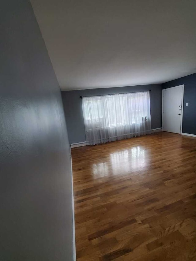 spare room with baseboards and wood finished floors