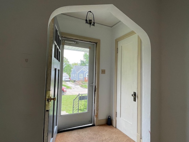 doorway featuring light carpet and arched walkways