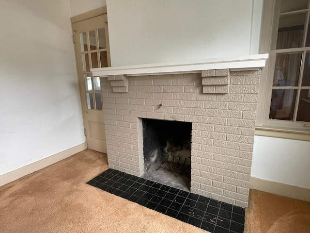detailed view of carpet, a brick fireplace, and baseboards