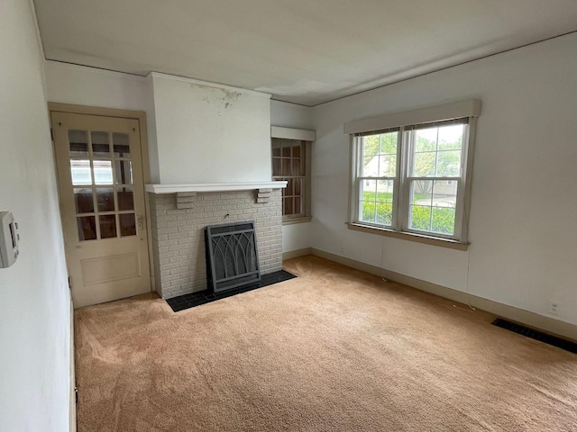 unfurnished living room with carpet flooring and a brick fireplace