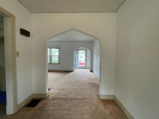 hall with carpet flooring, arched walkways, and baseboards