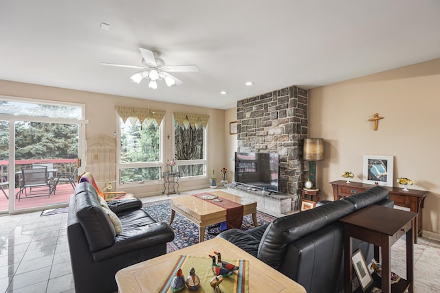 living room with a ceiling fan, baseboards, a fireplace, and light tile patterned floors