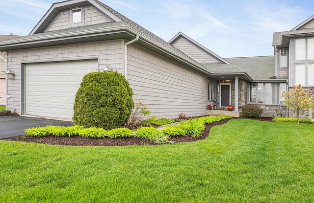 view of front of home featuring a shingled roof, a garage, a front lawn, and aphalt driveway