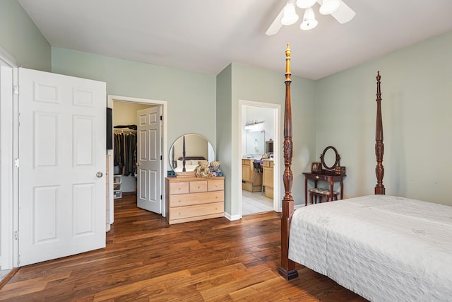 bedroom featuring a closet, baseboards, ensuite bathroom, wood finished floors, and a spacious closet