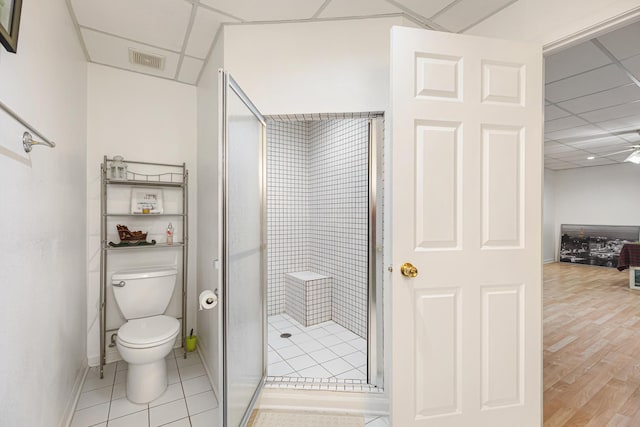 bathroom featuring a stall shower, a drop ceiling, baseboards, toilet, and visible vents