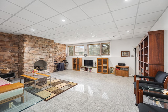 living room featuring baseboards, a drop ceiling, and a fireplace