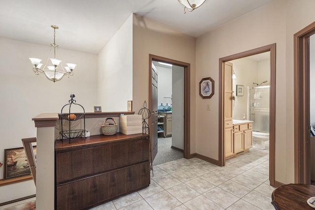hallway featuring light tile patterned flooring, a notable chandelier, and baseboards