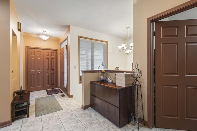foyer featuring a chandelier, baseboards, and light tile patterned floors