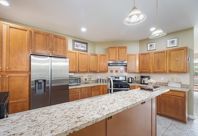 kitchen featuring stainless steel appliances, a toaster, under cabinet range hood, light tile patterned floors, and light stone countertops