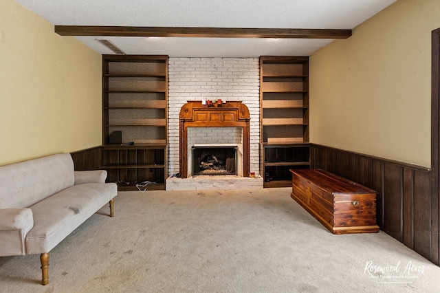 living area with carpet flooring, wainscoting, built in features, wooden walls, and beamed ceiling