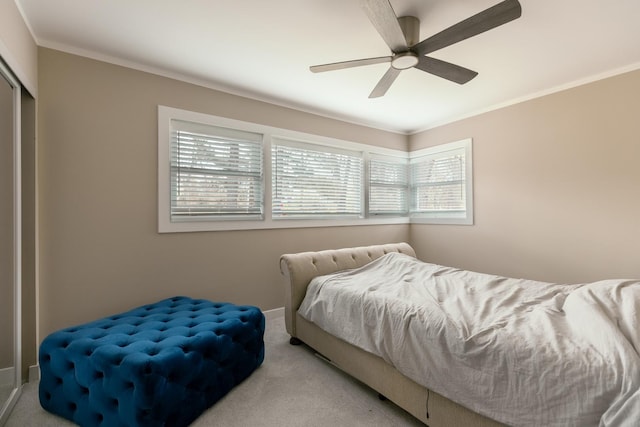 carpeted bedroom featuring ceiling fan, a closet, and ornamental molding