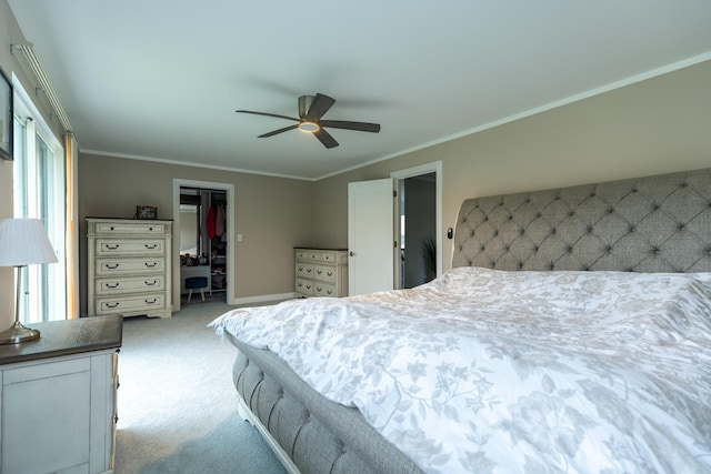 bedroom featuring a closet, light colored carpet, crown molding, a walk in closet, and baseboards
