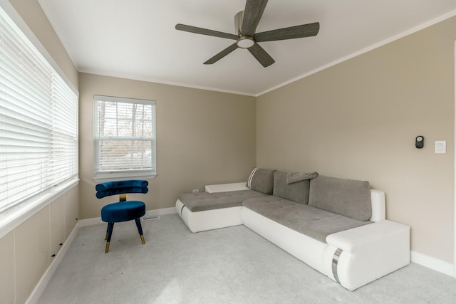 living area with crown molding, baseboards, ceiling fan, and carpet floors