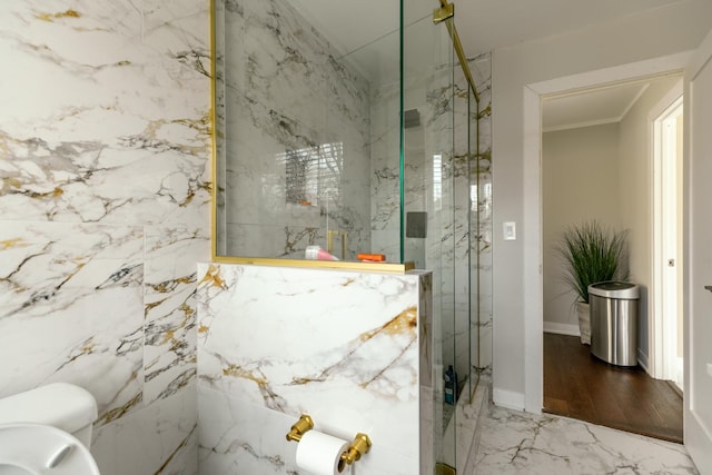 bathroom featuring toilet, a marble finish shower, baseboards, and ornamental molding