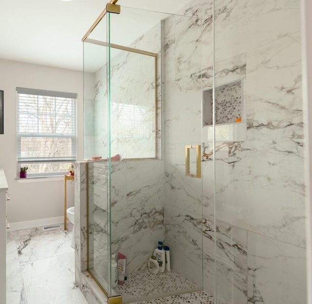 bathroom featuring vanity, a marble finish shower, and baseboards