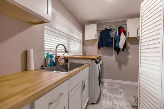 washroom with baseboards, a sink, cabinet space, and washer and clothes dryer