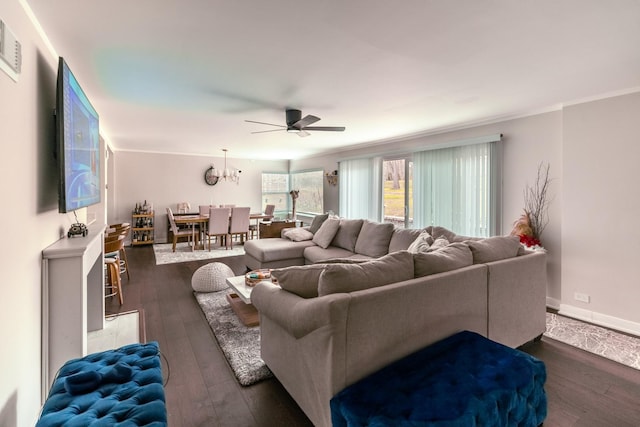 living room with a ceiling fan, baseboards, crown molding, and dark wood-type flooring
