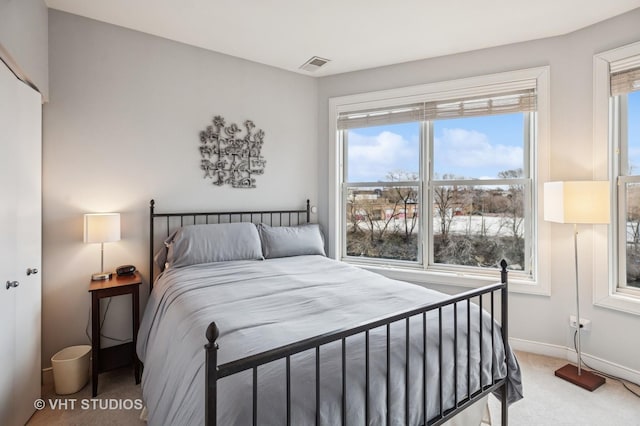 bedroom featuring baseboards, multiple windows, light carpet, and visible vents