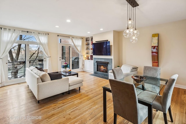interior space with built in features, a fireplace, recessed lighting, light wood-style flooring, and baseboards